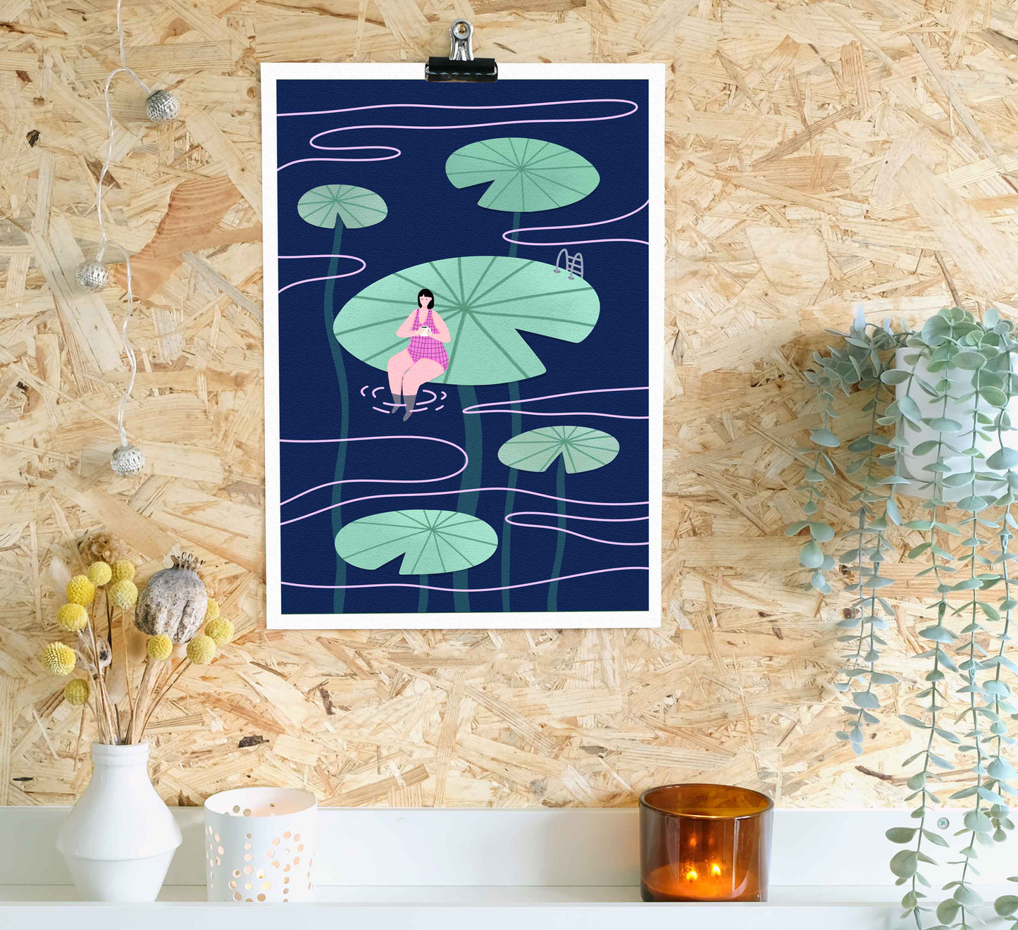 Framed artwork of a woman sitting on lily pads against a wooden wall.
